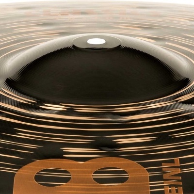 Prato de percussão preto brilhante com detalhes bronze numa mesa de madeira clara