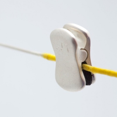 Prendedor de roupa metálico prateado num fio amarelo