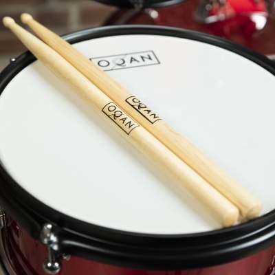 Tarola de bateria com pele branca e aro preto com baquetas em madeira clara em cima