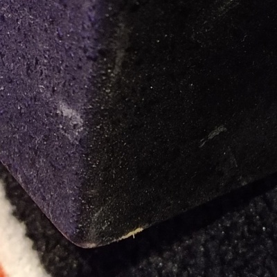 canto de objeto escuro com textura áspera sobre superfície escura macia