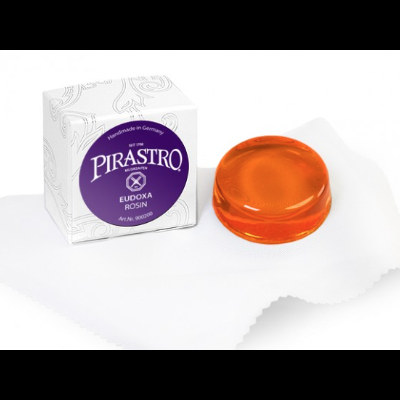 Resina âmbar translúcida ao lado da embalagem branca da marca Pirastro e pano branco