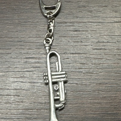 Porta-chaves metálico em forma de trompete em cima de superfície de madeira escura