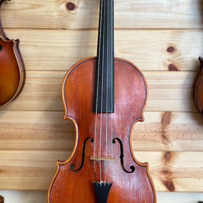 Violino de madeira castanho avermelhada com quatro cordas e painel claro