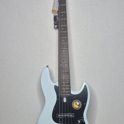 Baixo elétrico Marcus Miller V7 azul claro com quatro cordas e pedestal preto