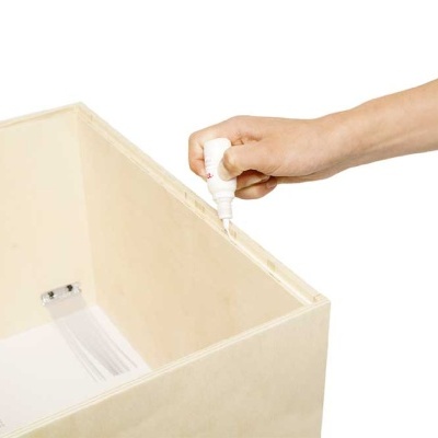 Caixa de madeira clara com mão aplicando cola