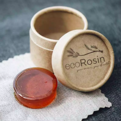 Pastilha de resina castanha translúcida junto a caixa cilíndrica de papel reciclado com texto ecoRosin