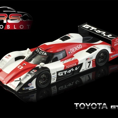 Carro de slot Toyota GT-One branco, vermelho e preto com várias inscrições sobre fundo preto.