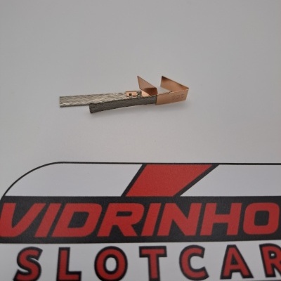 Peça metálica de cobre e metal prateado sobre superfície com logótipo VIDRINHO SLOTCAR.
