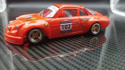 Miniatura de carro de corrida laranja com autocolantes sobre superfície de carbono.