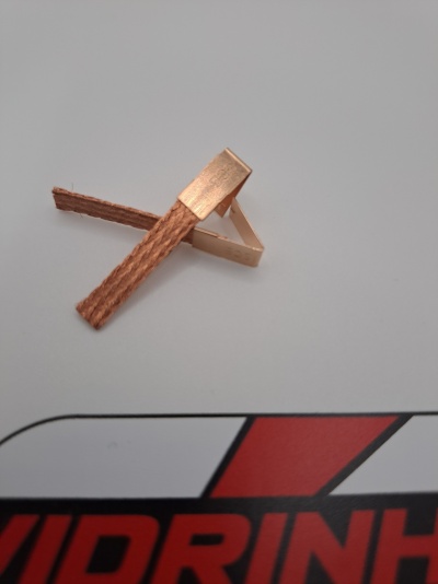 Pinça com ponta metálica dourada e corpo castanho sobre superfície branca com texto vermelho