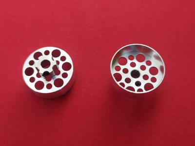 Acessórios metálicos cilíndricos com orifícios circulares sobre fundo vermelho