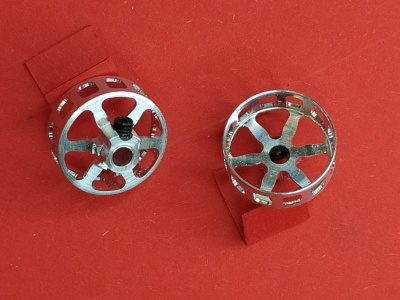 Dois anéis prateados com design circular em suportes vermelhos