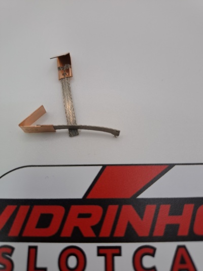 Duas peças metálicas de cobre sobre superfície branca com texto vermelho e preto