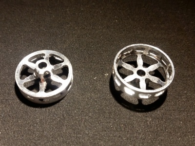 Duas peças metálicas circulares prateadas sobre fundo preto