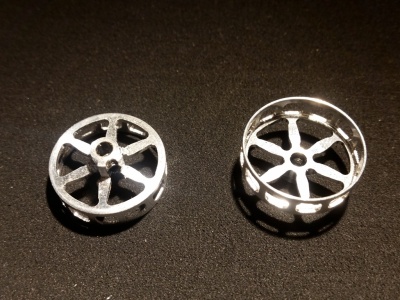 Duas jantes metálicas prateadas com sete raios sobre superfície escura