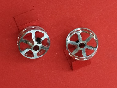 Botões de punho em metal prateado com design circular e recortes, sobre fundo vermelho