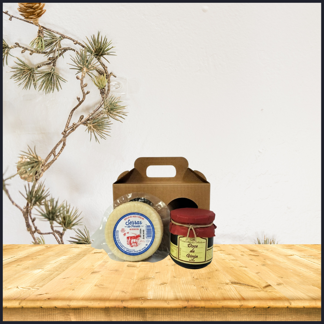 Mini Cabaz de Natal Conjunto com queijo redondo e frasco de doce numa mesa de madeira clara, embalagem castanha e ramo de pinheiro ao lado