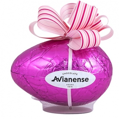 Ovo de chocolate embrulhado em papel rosa metálico com laço decorativo e rótulo oval branco