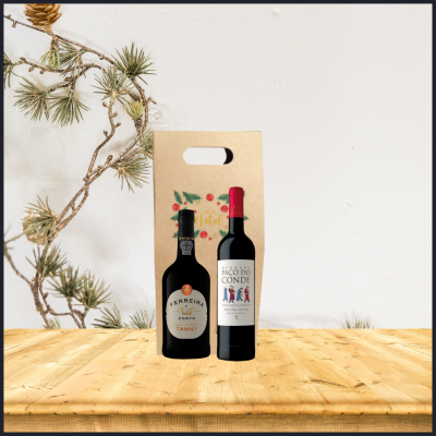 Duas garrafas de vinho numa mesa de madeira com saco de papel e ramo de pinheiro ao fundo.