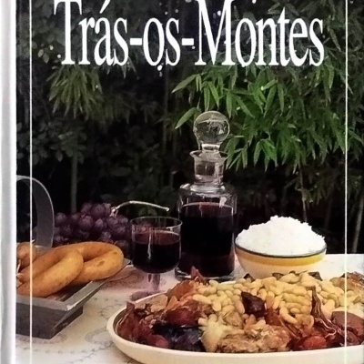 Livro com capa de cozinha regional portuguesa Trás-os-Montes e imagem de pratos tradicionais numa mesa