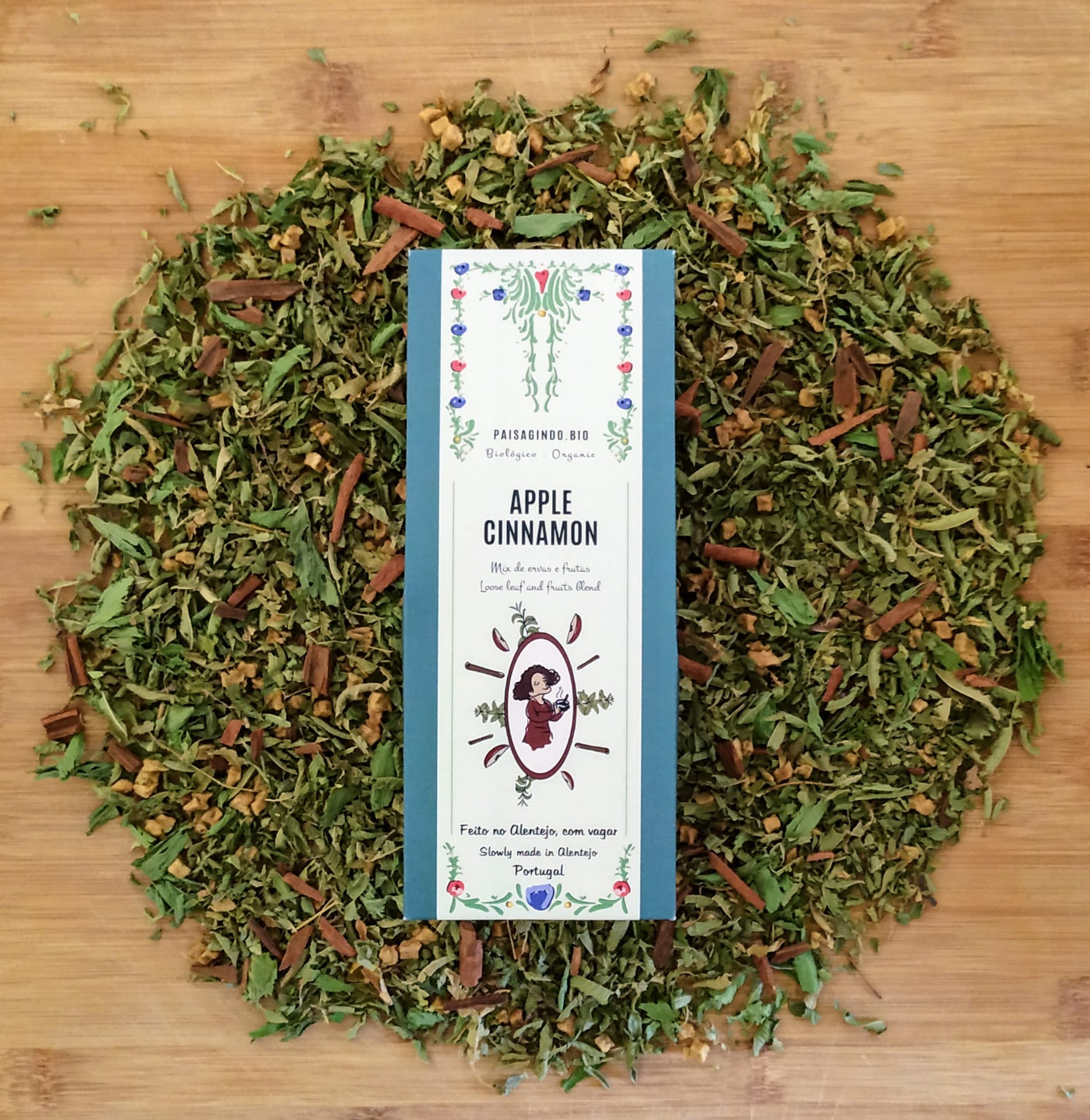 Lúcia in the Cinnamon with Apples (Apple & Cinnamon) Pacote de chá Apple Cinnamon rodeado por folhas secas e canela