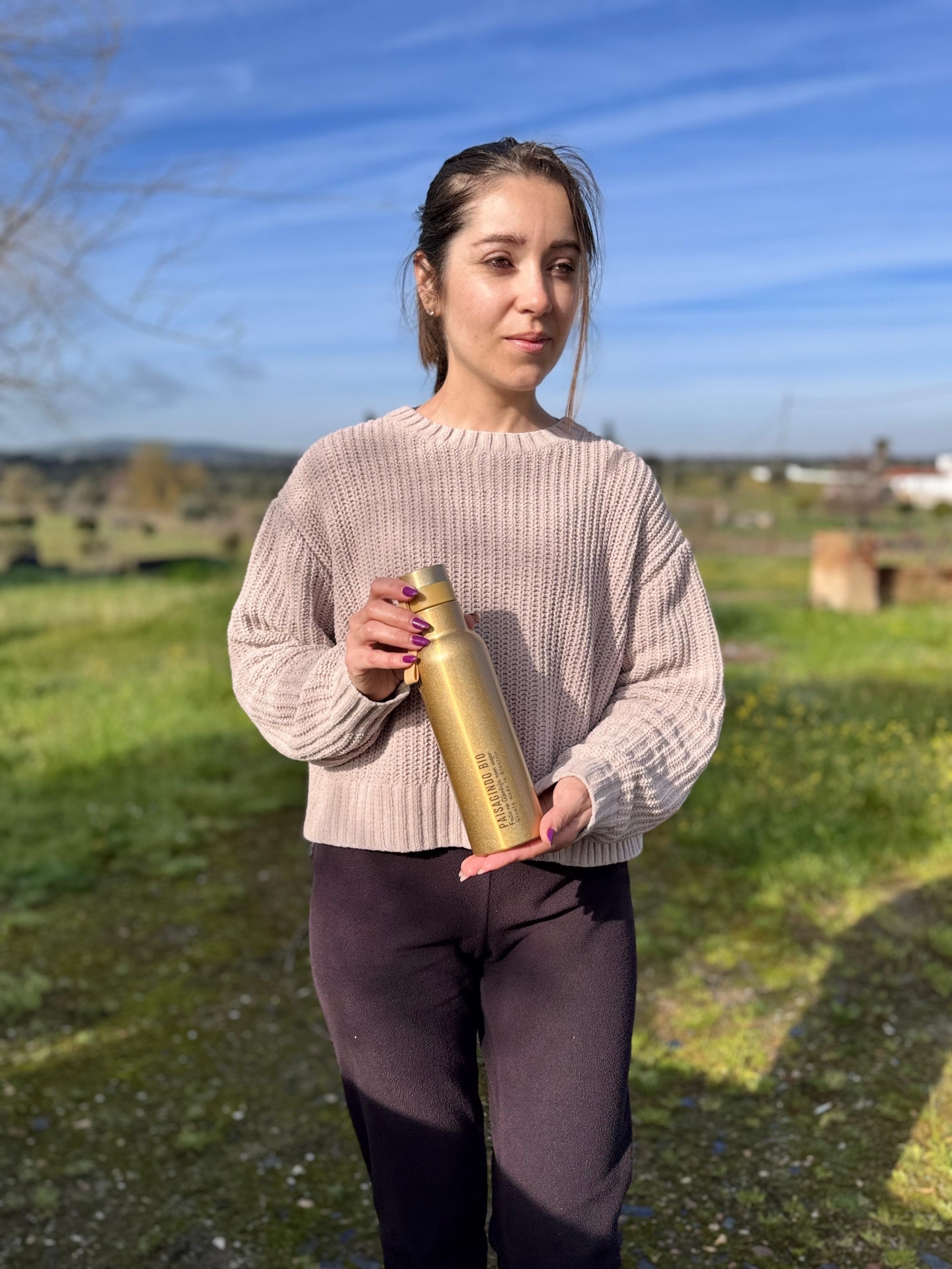 Garrafa térmica "dourada" em inox (530 ml) Mulher segurar garrafa metálica dourada em campo verde com céu azul