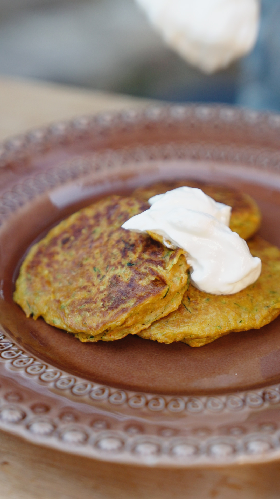 Bolinhos dourados com creme branco num prato castanho decorado