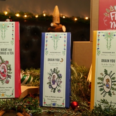 Caixas de chá natalícias com padrões florais e texto sobre mesa decorada