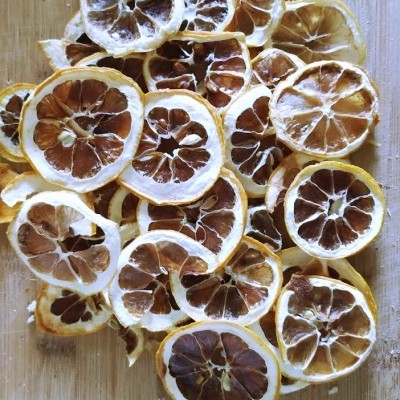 Fatias de limão seco amarelas e castanhas sobre superfície de madeira clara