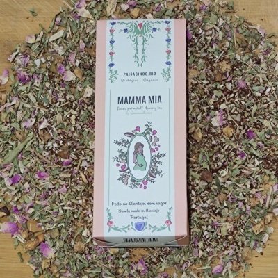 Caixa de chá Mamma Mia rodeada por folhas e flores secas sobre superfície de madeira