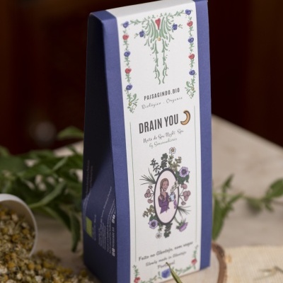 Embalagem de chá orgânico azul e branca com ilustração floral e mulher ao centro