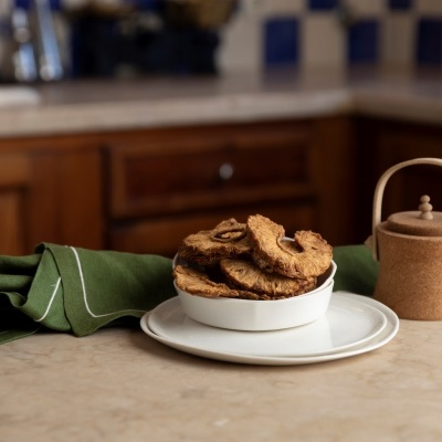 Tigela branca com bolachas, pano verde e jarra castanha numa bancada de cozinha