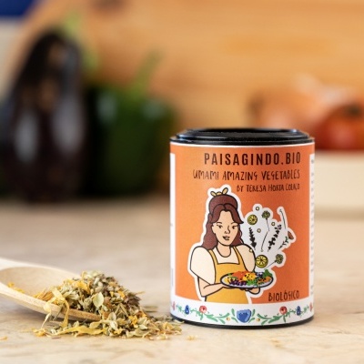 Embalagem cilíndrica laranja com ilustração e especiarias secas numa colher de madeira em bancada de cozinha