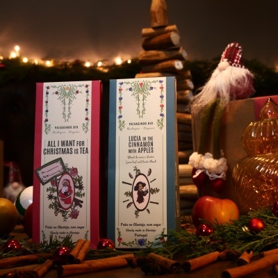 Caixas de chá natalícias em cenário decorativo com elementos naturais e luzes