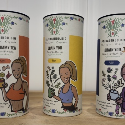 Três latas de chá orgânico Paisagindo.Bio com ilustrações de mulheres e textos Flat Tummy Tea e Drain You.