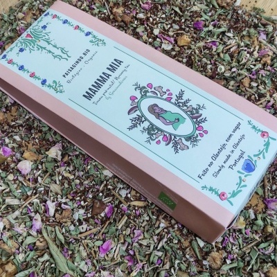 Caixa rosa da mistura de ervas 'Mamma Mia' sobre ervas secas e pétalas coloridas