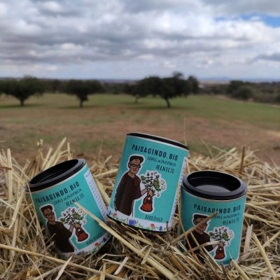 Três embalagens cilíndricas azuis e verdes com texto e ilustração sobre palha em ambiente rural