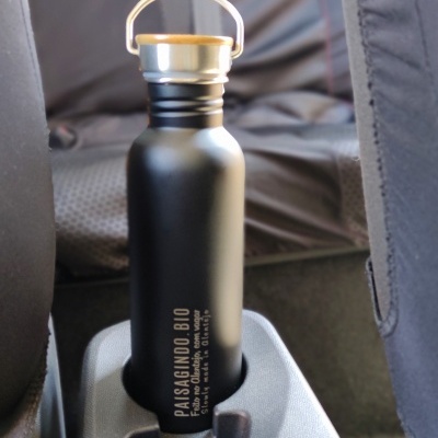 Garrafa preta com tampa de madeira no suporte de copos de um carro