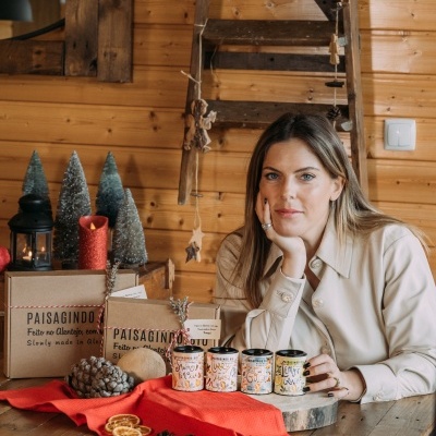 Mulher junto a frascos decorativos e caixas PAISAGINDO em ambiente rústico com decoração natalícia