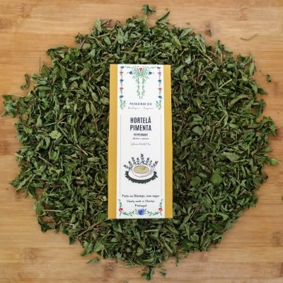 Pacote de hortelã-pimenta seco com rótulo e folhas secas ao redor em fundo de madeira