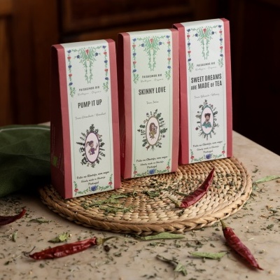 Três caixas de produtos sobre suporte de palha com pimentos e ervas ao redor.