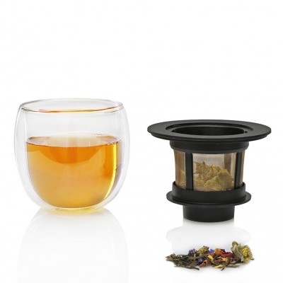 Copo de vidro duplo com chá e infusor de chá preto com filtro e folhas de chá coloridas.