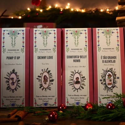 Seis caixas de chá coloridas com desenhos florais e texto em inglês, em ambiente decorado para Natal