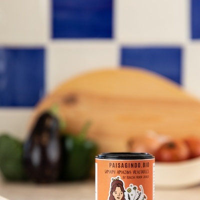 Frasco de ervas aromáticas PAISAGINDO.BIO com colher de madeira e azulejos azul e branco ao fundo