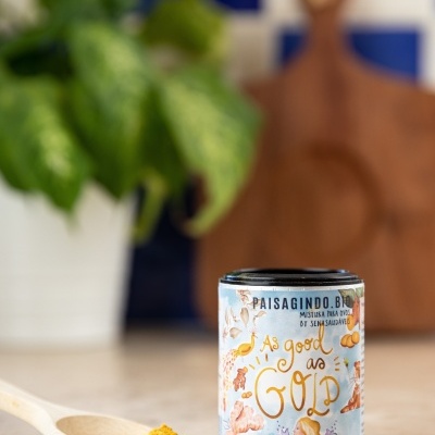 Frasco de especiarias ao lado de colher com pó amarelo em superfície clara