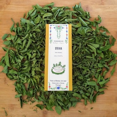 Pacote de Stevia rodeado por folhas secas verdes sobre madeira