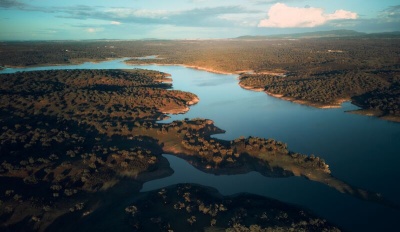 Rio serpenteando entre vegetação e céu ao entardecer