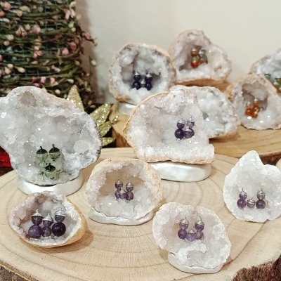 Geodos de quartzo branco com brincos coloridos em exposição sobre madeira