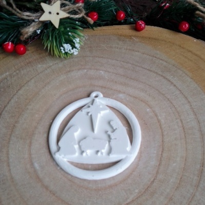 Enfeite de Natal de presépio branco sobre superfície de madeira com decoração de Natal