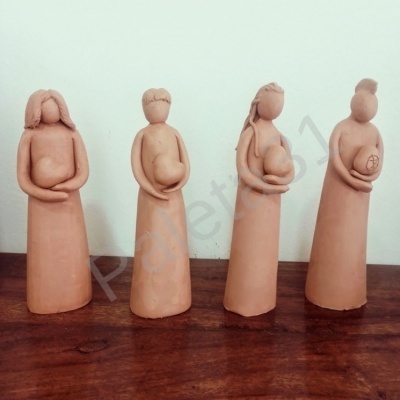 Conjunto de quatro figuras femininas em cerâmica terracota em cima de mesa de madeira.